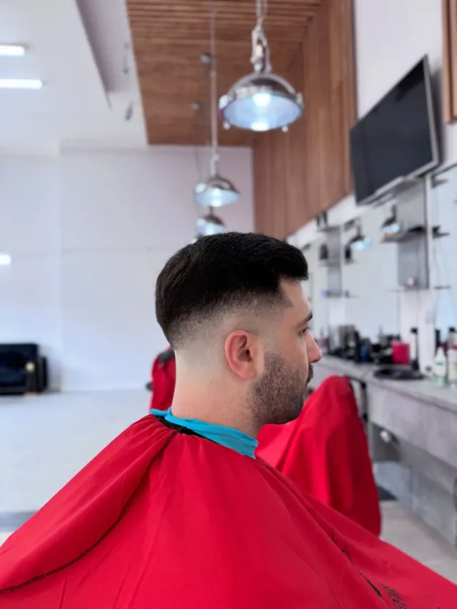 A textured crop with a fade, seen from behind, under the wood-slat ceiling and pendant lights