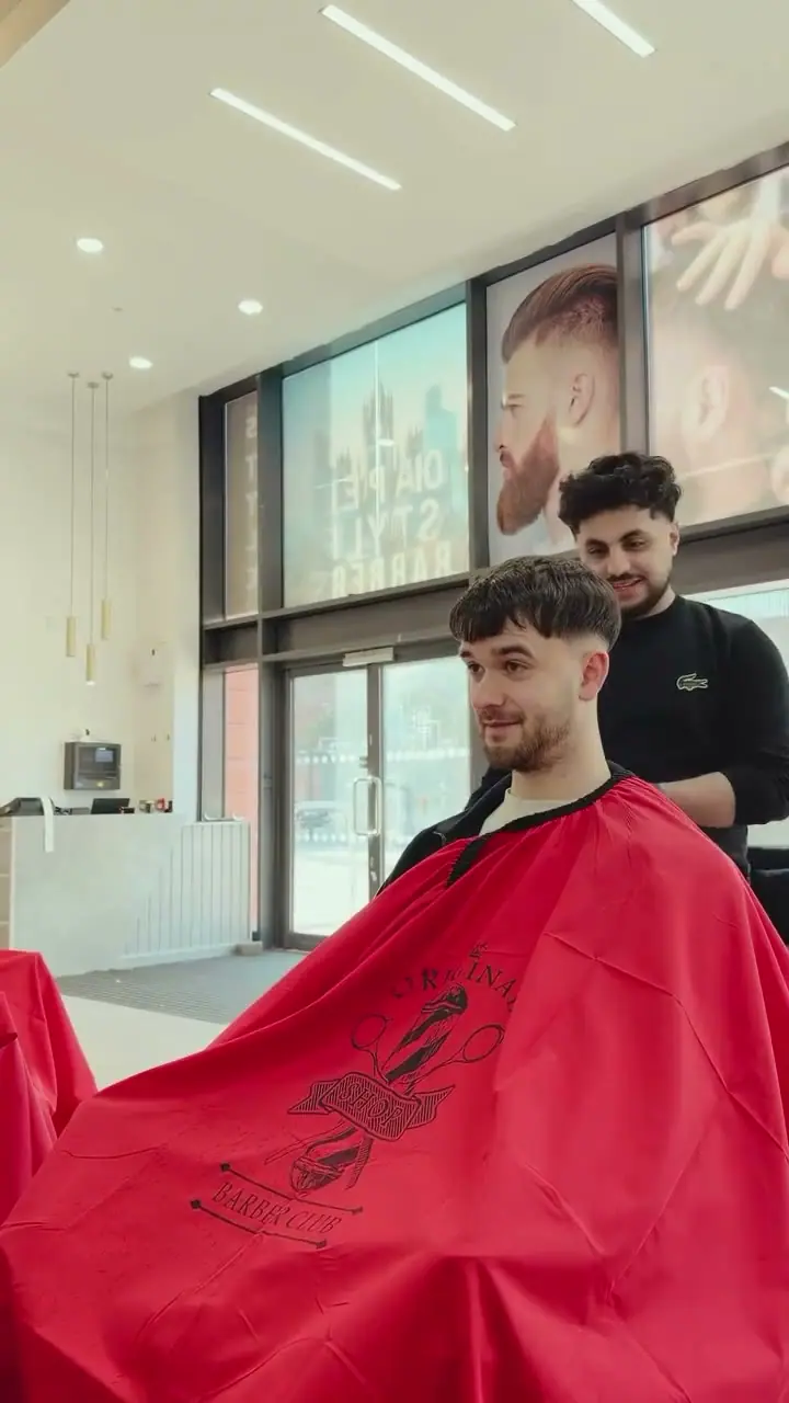 A barber finishing a cut and showing the result